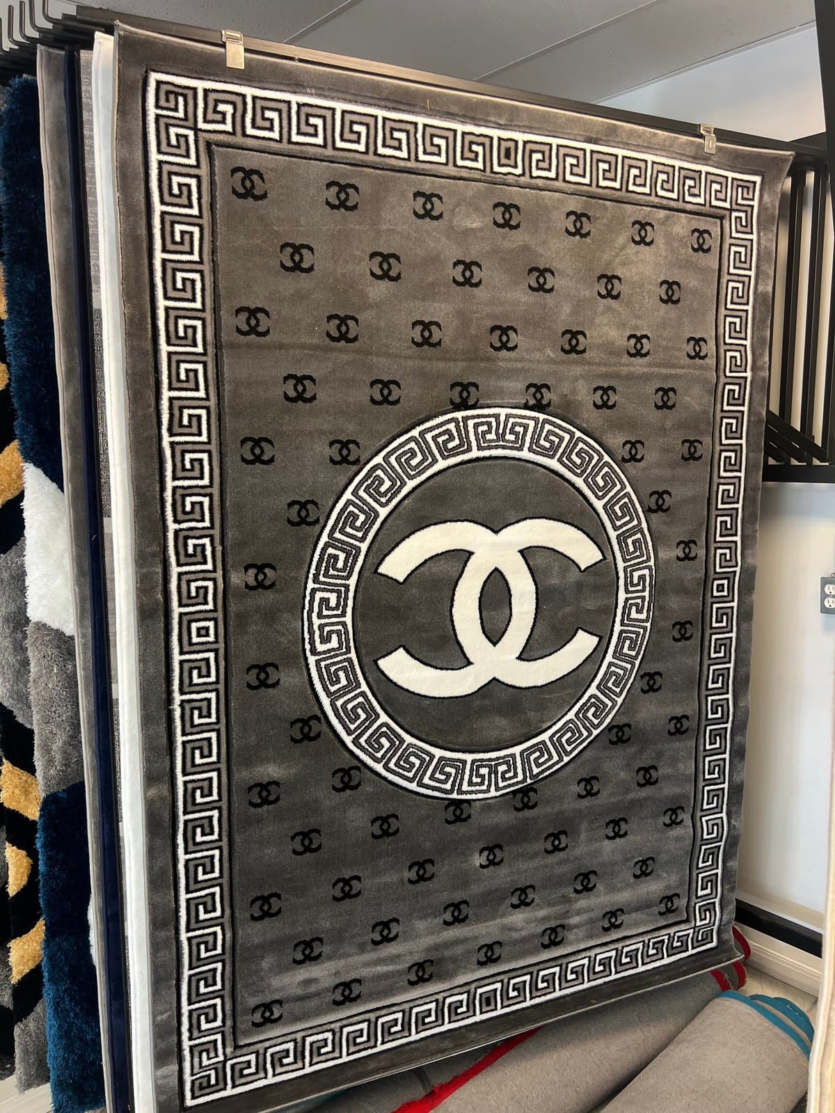 Luxury branded blanket with interlocking CC logo and Greek key border pattern on gray fabric