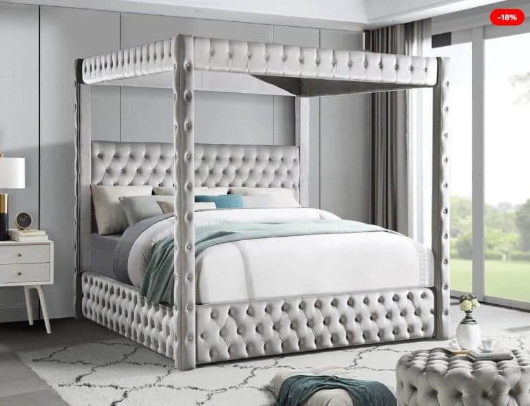Elegant upholstered four-poster canopy bed with tufted headboard and footboard in a modern gray bedroom with large windows