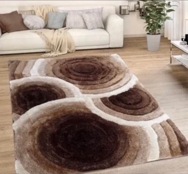 Modern living room with cream sofa and brown and beige spiral-patterned area rug on wooden floor