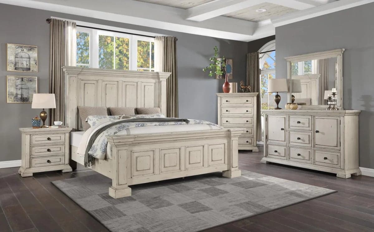 Complete bedroom furniture set with cream-colored wooden bed, nightstands, dresser, and mirror in a gray room with hardwood floors