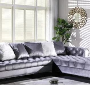 Grey velvet corner sofa in modern living room with large windows, decorative pillows, and wall decor. Product on sale for $1,599.00