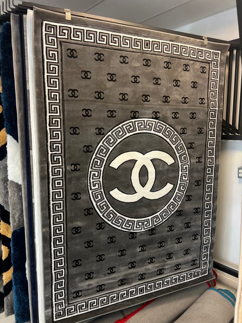 Luxury branded blanket with interlocking CC logo and Greek key border pattern on gray fabric