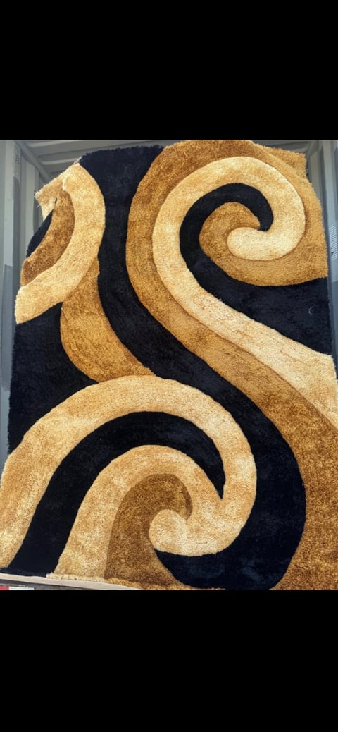 Modern area rug with abstract swirling design in gold, tan, and black colors