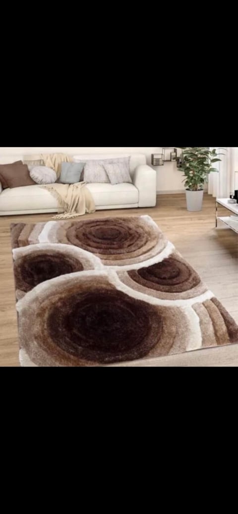 Modern living room with cream sofa and brown and beige spiral-patterned area rug on wooden floor