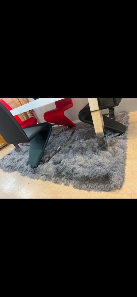 Modern chairs in red, black, and natural tones arranged on a gray shag rug in an interior design showroom