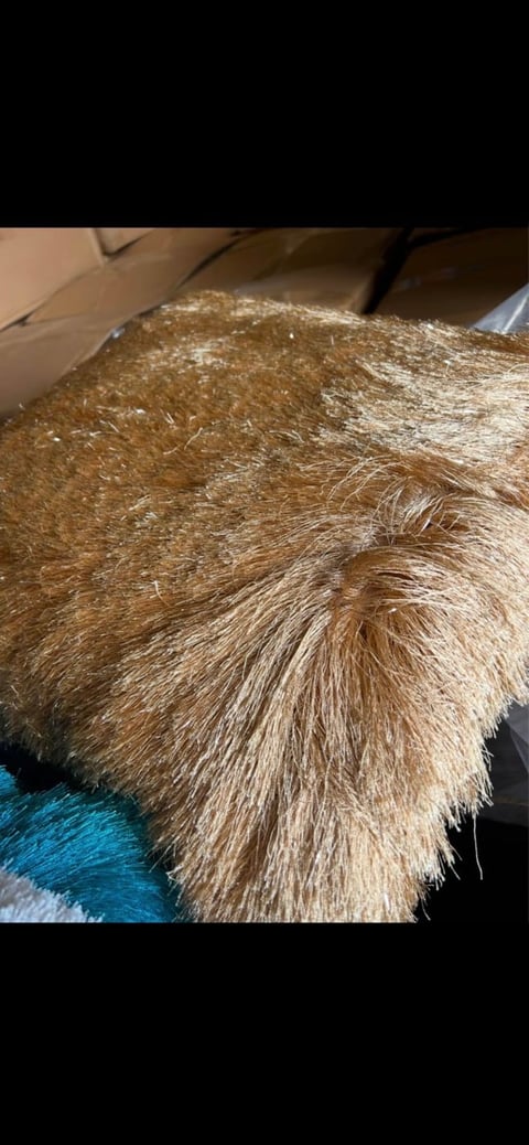 Close-up of a brown and tan furred animal resting on a blue and white fabric surface, showing detailed texture of its coat.