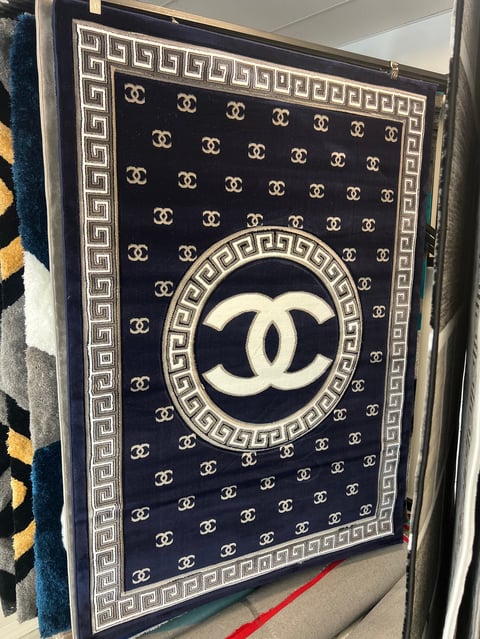 Black and white fabric with repeating CC logos and a large interlocking CC symbol in the center surrounded by a Greek key border pattern